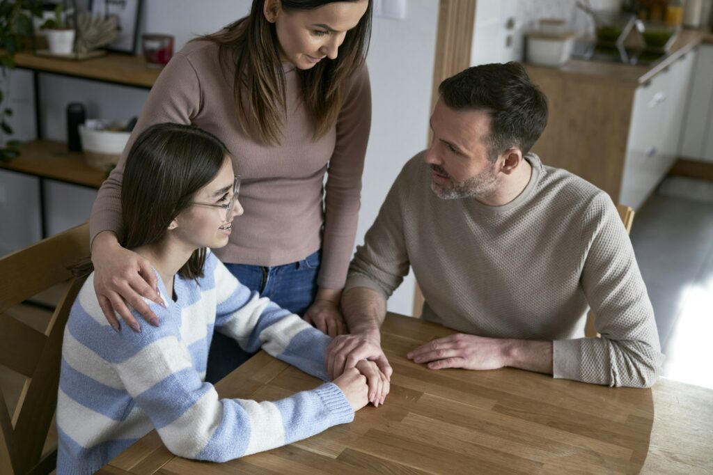 Caucasian parents talking with teenager girl and sitting around the table