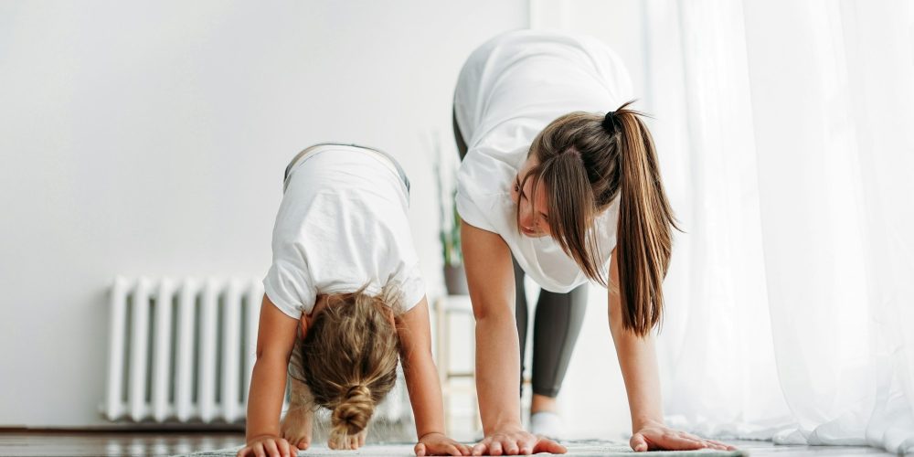 Happy mom and little daughter doing morning exercise together